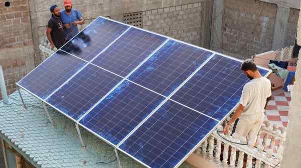 Technicians work on&nbsp;solar&nbsp;panels installed on the roof of a house&nbsp;in Karachi on June 8. Solar panels, mostly from China, are spreading across Pakistan as residents seek solutions to outages and hefty bills.