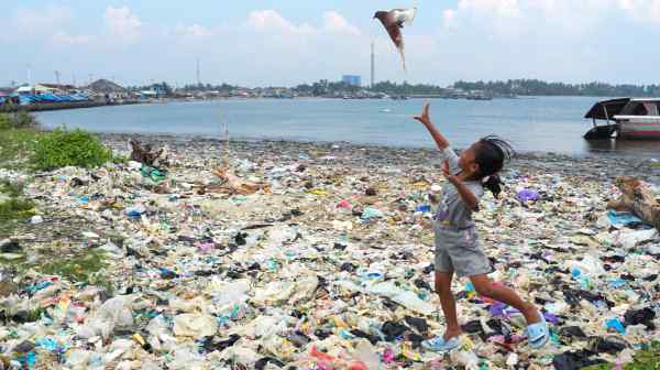 A girl chases a bird atop piles of dirty plastic waste&nbsp;washed up on Labuan Beach in western Java, Indonesia. Experts say much of the trash has been imported via "waste trafficking" from developed countries. (Photo by Dimas Ardian)