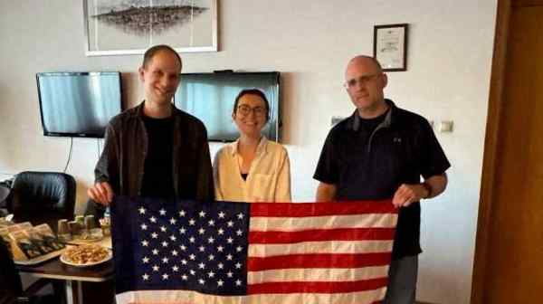 Evan Gershkovich, Alsu Kurmasheva and Paul Whelan, who had all been detained in Russia, pose with a U.S. flag in this undated handout photograph obtained Aug. 1. (U.S. government via Reuters)