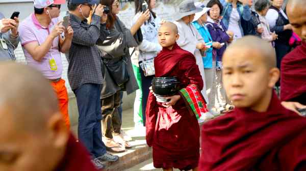 Tourists snap photos of Buddhist monks while watching the morning alms ceremony in Mandalay, Myanmar. (Photo&nbsp;by Charukesi Ramadurai)