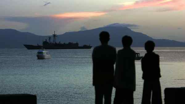 Boys watch an Australian Navy ship maneuver off the coast of Dili, the capital of East Timor: the country's long-held dream to create a domestic petroleum industry is in jeopardy.