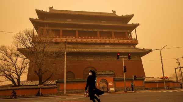 A woman walks past Drum Tower during morning rush hour as Beijing is hit by a&nbsp;sandstorm on March 15.&nbsp;