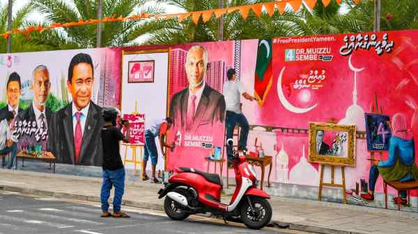 A motorcyclist takes photos of a decorated wall in Male on Sept. 6, ahead of the country's presidential election. Incumbent&nbsp;Ibrahim Mohamed Solih is the favorite, while&nbsp;Male mayor Mohamed Muizzu is considered his top challenger.