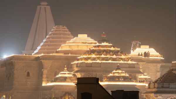 Laborers stand on top of the illuminated grand temple of Lord Ram ahead of its opening in Ayodhya in India.