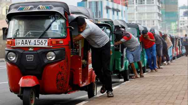 Drivers push auto rickshaws in a line to buy gasoline from a fuel station&nbsp;in Colombo, Sri Lanka, in July 2022 amid an economic crisis.