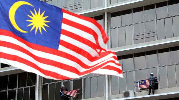 Workers hang Malaysian flags in Kuala Lumpur.