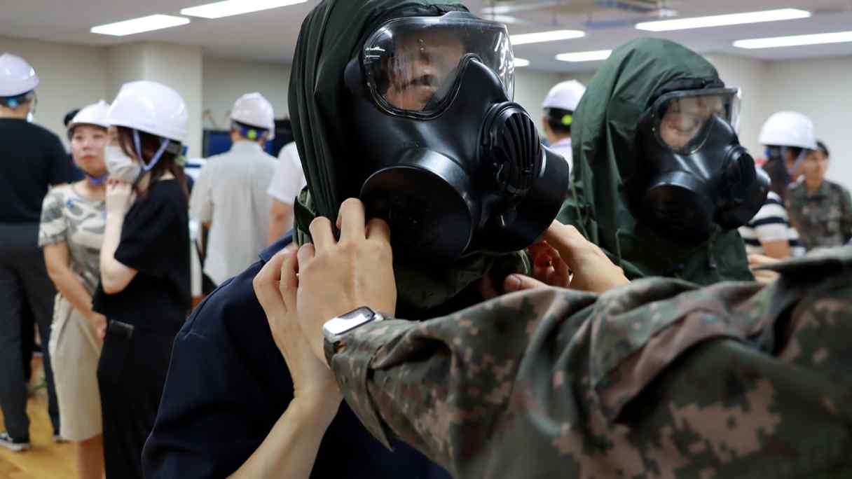 Soldiers instruct&nbsp;employees on how to use gas masks in the basement of a government building in Seoul, during an air raid drill on Aug. 22. (Photo by&nbsp;Ahn Seong-bok)