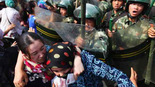 Uyghur women protest in front of policemen in Urumqi on July 7, 2009. The unrest, which started two days earlier, prompted a harsh crackdown and led to much stricter governance in the Xinjiang region.