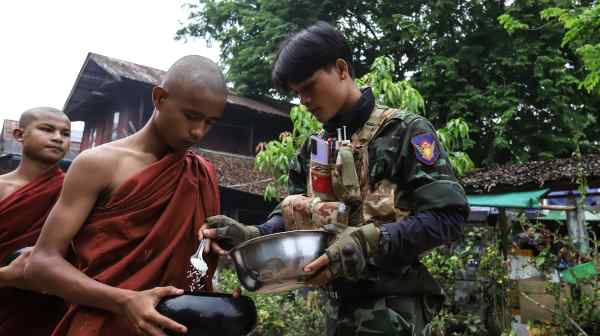 Monks collect alms from a fighter in the anti-regime People's Defense Force in Tagu, a town in&nbsp;southern Myanmar's&nbsp;Tanintharyi Region. (All photos by Valeria Mongelli)