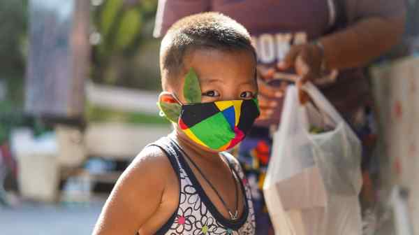 A child wears a mask in Thailand slum. The World Bank's forecast of a "third shock" could&nbsp;devastate economic growth and increase poverty across developing Asia. (Photo by Akira Kodaka)